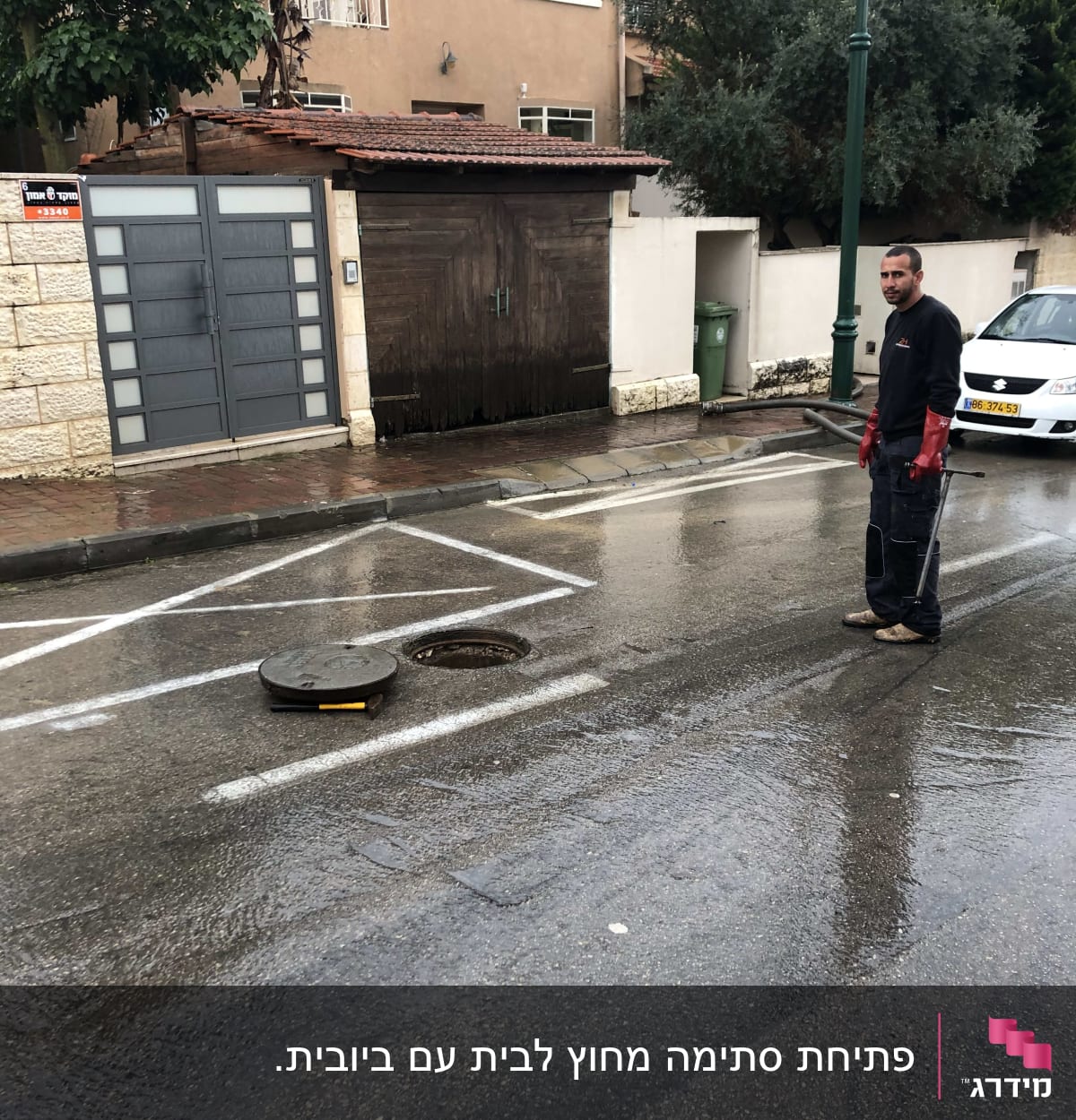 אדם ליד פתח ביוב פתוח בכביש רטוב